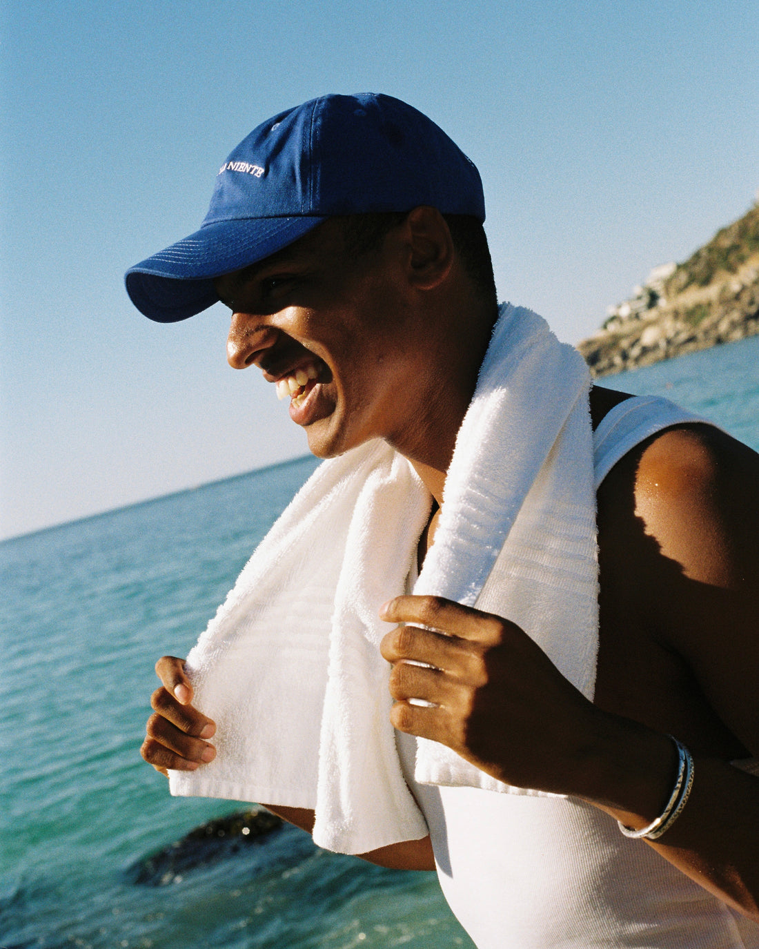 Lachender Mann am Strand mit Blauem Cap und weissem Tuch um den Hals